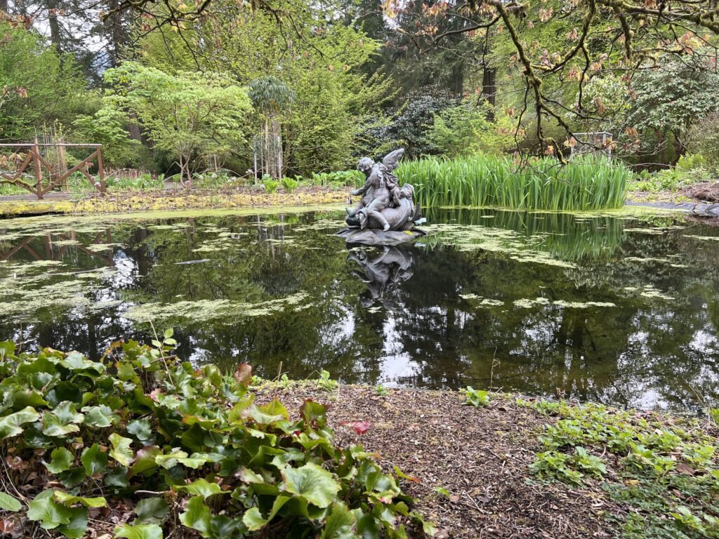 Pond with bronze sculptures and ducks swimming through the reeds